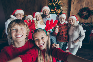 Wall Mural - Self photo of large family meeting together with couple of brother sister taking selfie on background of their relatives parents grandparents and christmas tree in lights