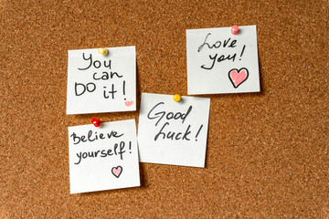 Handwritten inspirational supportive lettering on a sticker on a cork board. Background and texture.
