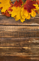 Wall Mural - autumn maple leaves on top view wooden table. vertical frame with top side foliage and copy space.
