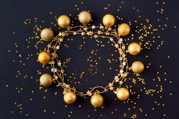 flat lay frame with gold christmas balls and golden confetti on a dark background