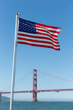 Stars And Stripes Flying With The Golden Gate Bridge Behind