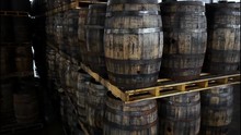A Forklift Slides In And Lifts Up A Pallet Of Wooden Barrels Off A Stack Of Oak Whiskey Casks At A Distillery