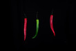 Drei bunte schwebende chillis auf schwarzem Hintergrund