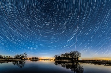 Poster - Beautiful shot of a lake with the reflection of tree silhouettes and the abstract sky