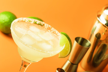 Lime margarita alcoholic cocktail with silver tequila, liqueur, lime juice, sugar syrup, salt and ice, festive trendy orange background, copy space