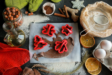 The process of making christmas cookies. Girl hands make the dough. Ingredients for baking a pie: flour, confectionery, dishes, kitchen utensils, spruce cookies figure on a dark background.Christmas g