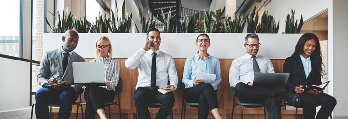 Diverse businesspeople smiling while waiting together in an offi
