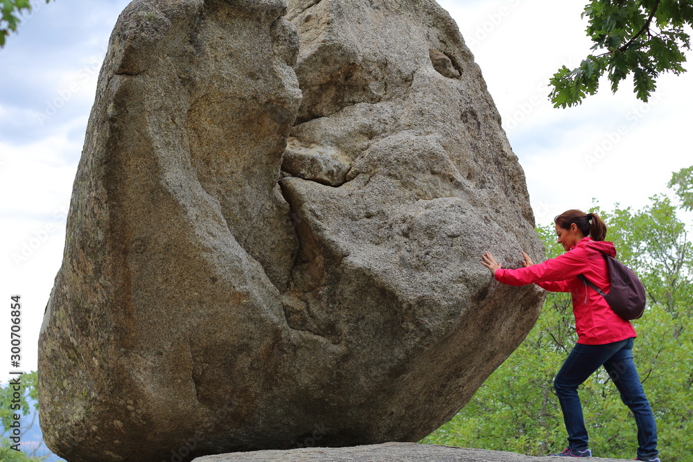 Mujer intentando el reto de empujar una roca gigante con esfuerzo en ...