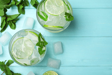 Canvas Print - Flat lay composition of cocktail with vodka, ice and lime on blue wooden table. Space for text