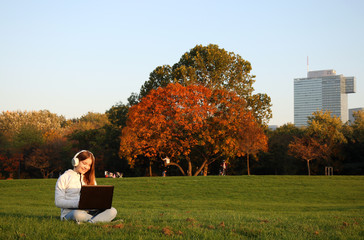 Wall Mural - happy teenage girl typing on laptop in Donaupark Vienna autumn season