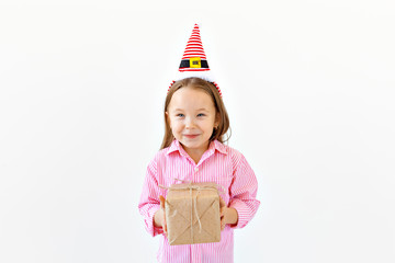 Wall Mural - Smiling funny child in Santa red hat holding gift box in hand over white background with copyspace. Christmas concept.