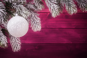 Wall Mural - Christmas ball on spruce frosty brunches against wooden background. Xmas and New Year background