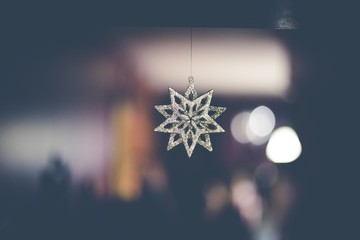 Sticker - Closeup shot of a beautiful snowflake hanging in the air with bokeh lights in the background