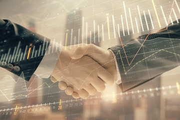 Double exposure of financial graph on cityscape background with two businessman handshake. Concept of stock market deal