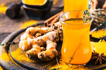 Sticker - Healthy vegan turmeric golden tea with honey in glass cup on wooden tray. Herbal healing spicy tea