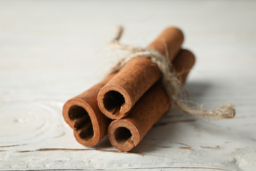 Cinnamon sticks on white wooden background, space for text and close up