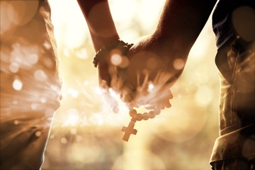 Wall Mural - Couple praying together. Holding rosary in hand.