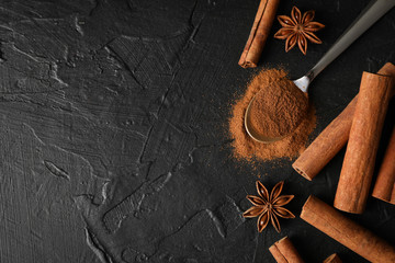 Poster - Cinnamon sticks, anise and spoon on black background, space for text