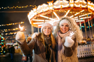 Photo of two women on background of carousel in park