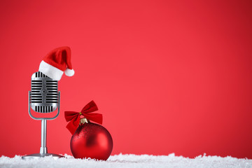 retro microphone with santa hat and bauble on red background