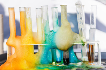 glass test tubes with liquid in it and colorful foam in science research lab. failed experiment conc