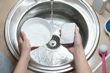 Woman Is Washing A Dishes By Sponge In The Kitchen Sink. Dish Washing, Washing Up Concept.