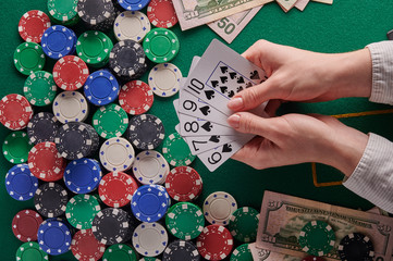 A player in a poker casino shows cards with a combination of straight on the background of chips and money of dollars. Victory, success. Gaming business.