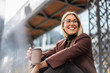 © Daniel Ingold/Westend61 - Happy young businesswoman with takeaway coffee in the city