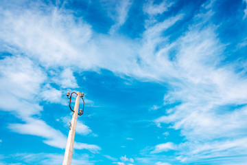 Old pole to hold disused electrical cables with blue sky and clouds, copy space.