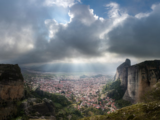 Wall Mural - sunrays shining through moody clouds over kalabaky city nestled between mountain cliffs
