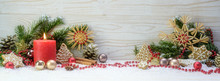 Burning Red Candle With Fir Branches And Christmas Decoration Against A White Wooden Background, Panoramic Format With Copy Space