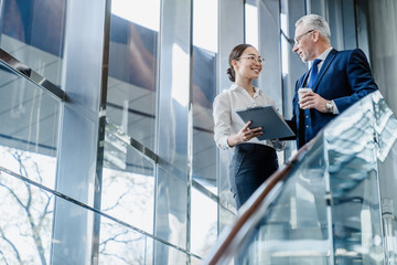 senior businessman and young asian female working with documents together in office lobby