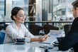 © InsideCreativeHouse - Asian businesswoman holding a paper in hand and showing analitics while talking to her business colleague