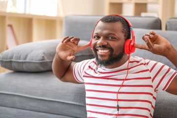 Wall Mural - Handsome African-American man listening to music at home