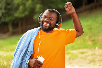 Wall Mural - Handsome African-American man listening to music outdoors