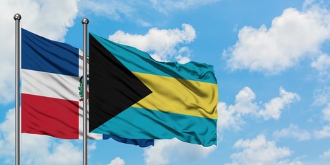 Dominican Republic and Bahamas flag waving in the wind against white cloudy blue sky together. Diplomacy concept, international relations.