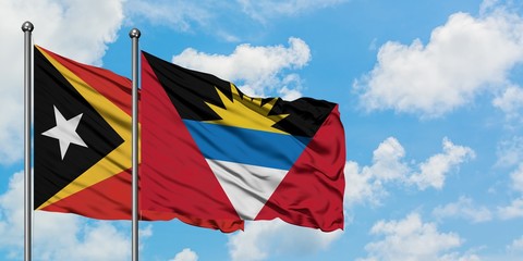 East Timor and Antigua and Barbuda flag waving in the wind against white cloudy blue sky together. Diplomacy concept, international relations.