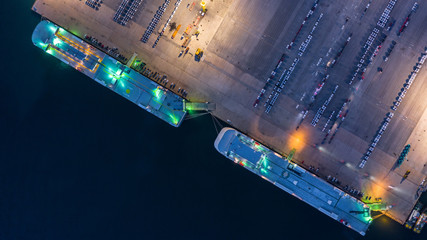 Wall Mural - Aerial top view car carrier vessel at night, rows of new cars at night waiting to be dispatch and shipped import export new cars.