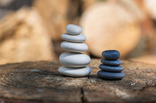 White Black Stone Cairns, Poise Light Pebbles On Wood Stump In Front Of Brown Natural Background, Zen Like, Harmony And Balance