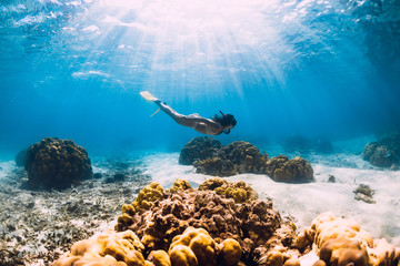 Woman freediver glides over sandy sea with yellow fins in transparent sea. Freediving in Mauritius