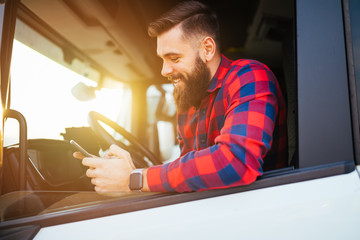 Young handsome bearded man using smart phone in his truck.