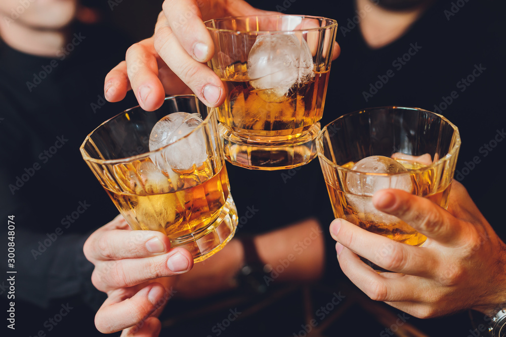 Clinking glasses with alcohol and toasting, party. whiskey ice - obrazy, fototapety, plakaty 