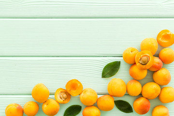 Fruit frame. Apricots and leaves on green wooden background top view space for text