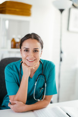 Wall Mural - Young female doctor in medical office. Portrait of beautiful female doctor sitting in the clinic office.