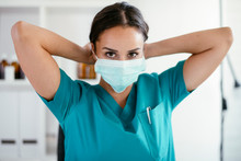 Young Female Doctor In Medical Office. Beautiful Female Doctor Putting Mask On. Close Up.