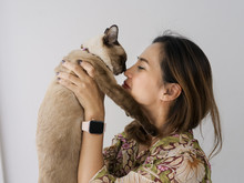 Asian Woman Holding  And Kissing Her Cat With Window Light At Home.