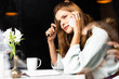 © LIGHTFIELD STUDIOS - thoughtful woman talking on smartphone in cafe with notepad and cup of coffee