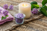 Fototapeta Lawenda - Towel, sea salt, candle and lilac flowers on wooden background.