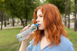 © lokisurina - pure drinking water, young red-haired girl with a bottle of water, bottled water