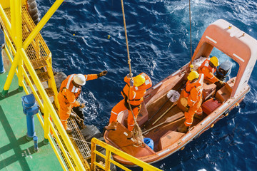 Fast rescue craft being deployed from a construction barge at oil field